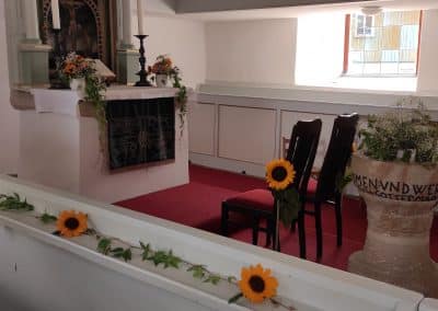 Sommerliches Altargesteck mit strahlenden Sonnenblumen und Rosen für eine Hochzeit.
