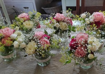 Meisterhafte Tischgestecke mit rosa und weißen Rosen und viel Schleierkraut für eine Hochzeit in Dresden.
